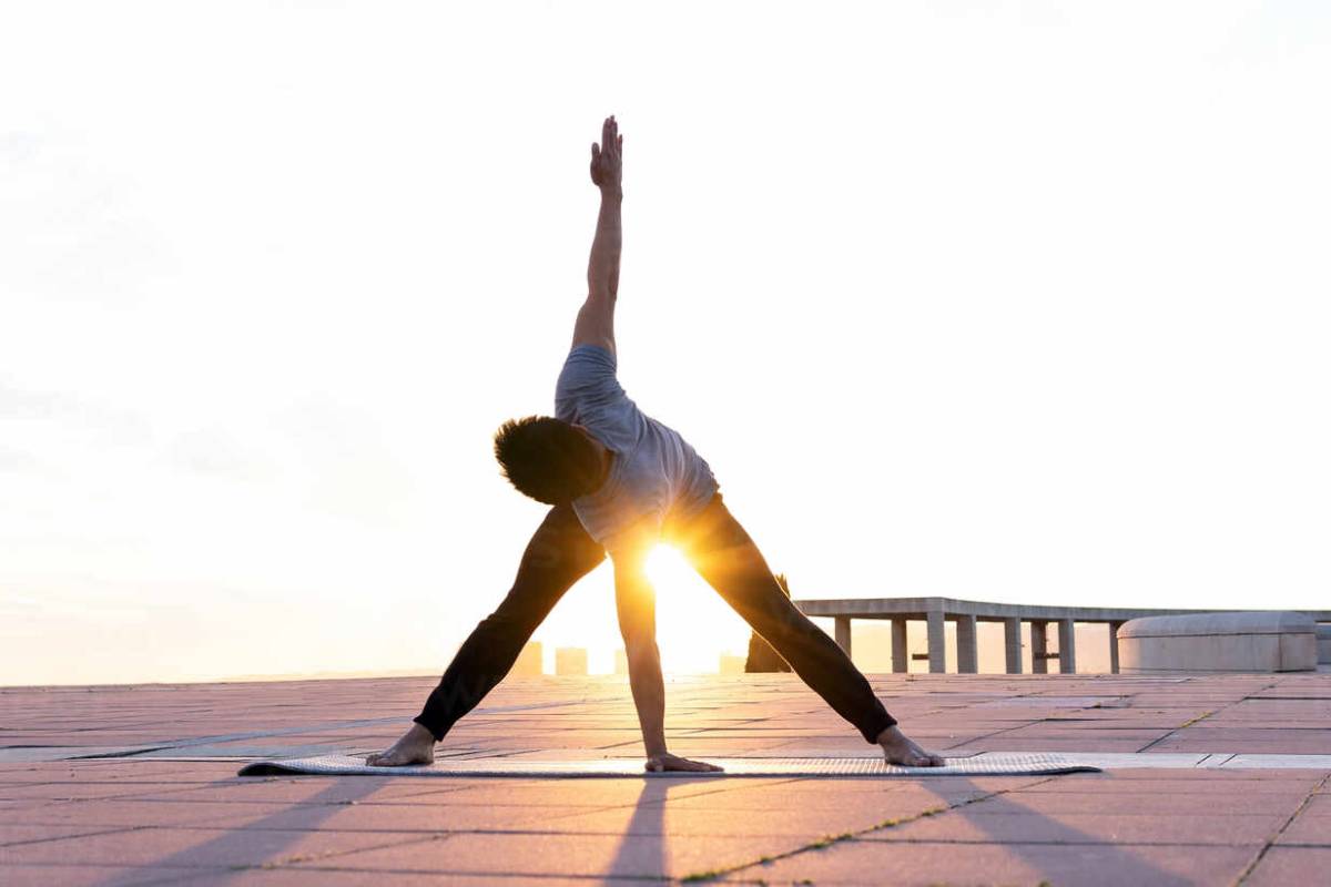 Unrecognizable male in activewear standing on yoga mat in Prasarita Padottanasana and practicing mindfulness while stretching