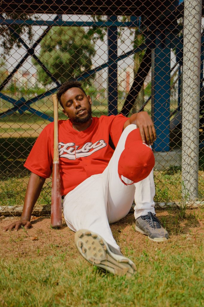 Giocatore di baseball in uniforme rossa che riposa appoggiato a una recinzione