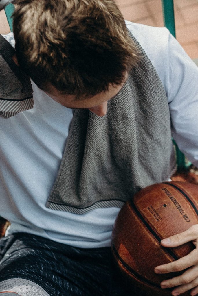 Giocatore di basket seduto con un asciugamano sulle spalle, in pausa
