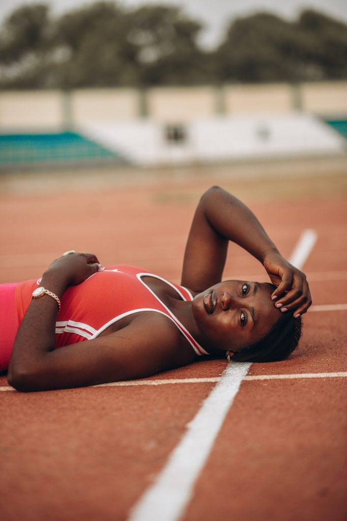 Donna in tenuta sportiva rilassata sulla pista di atletica dopo l'allenamento