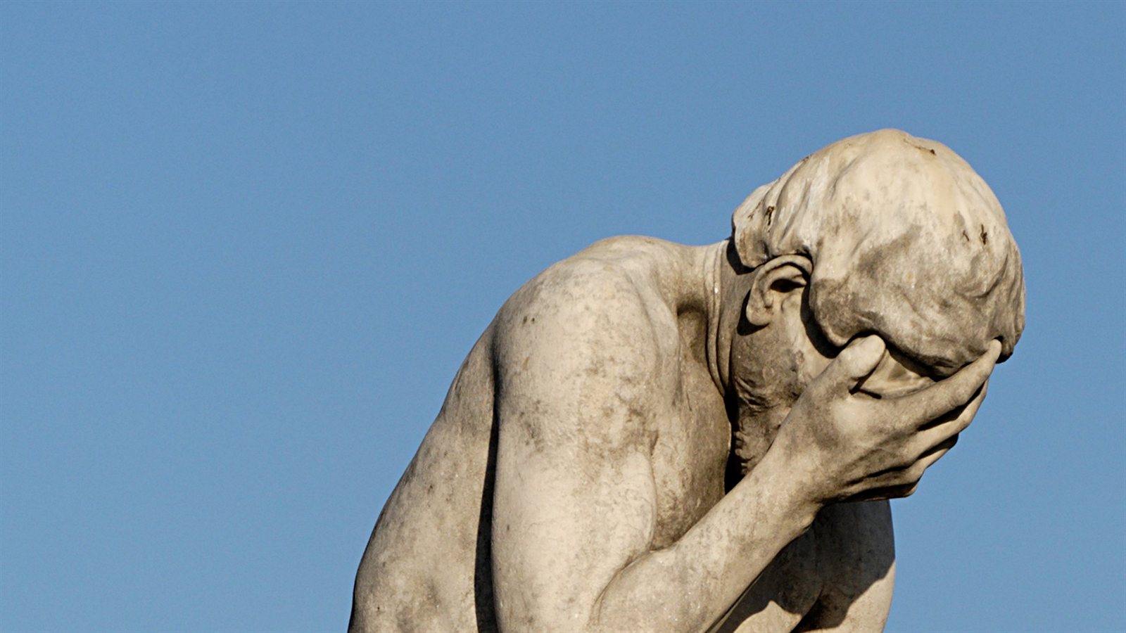Statua di un uomo che si copre il volto con la mano, il classico gesto del facepalm